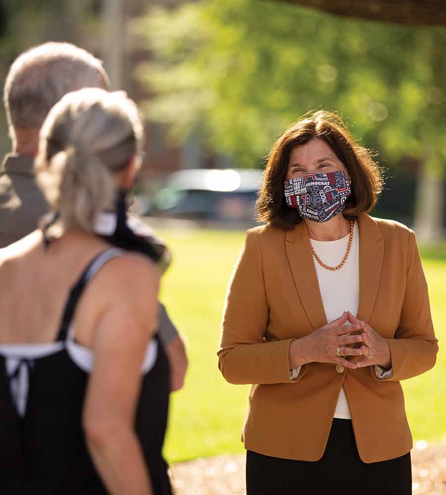 Cinde Warmington discussing policy with two young adults at the park while wearing a mask